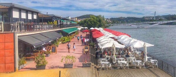 Terraza a la orilla del río con mesas al aire libre y vistas del río.