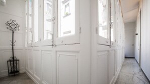 A hallway with white paneled walls and doors, a metal floor lamp, and a marble floor. - Largodonnaregina home vacation home 2 bedroom apartment historic center (Napoli)