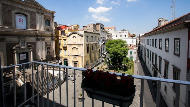 A balcony with a flower pot and a view of a city street with buildings. - Largodonnaregina home vacation home 2 bedroom apartment historic center (Napoli)