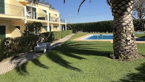 Un bâtiment à deux étages doté d’un balcon, d’une piscine et d’un palmier.