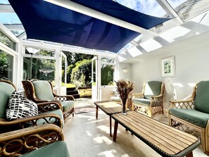 A sunlit room with wicker furniture, a table, and a large window.