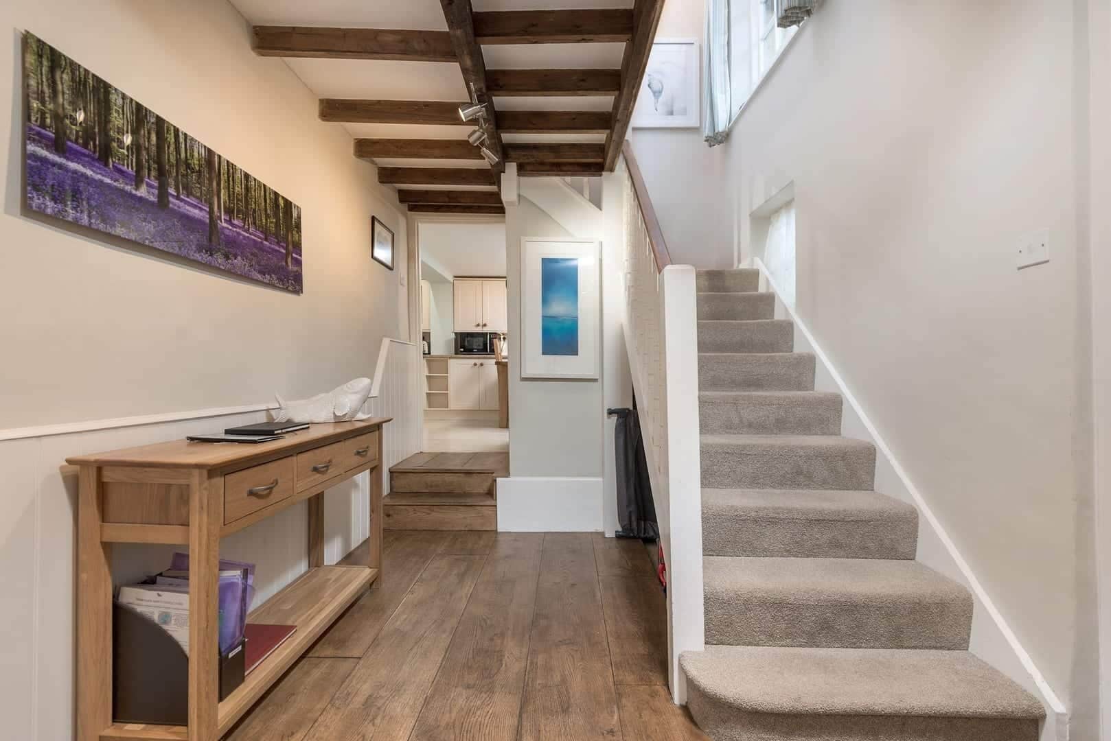 Ein Flur mit einem Holztisch, einer Treppe und einer Küche im Hintergrund.