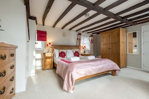 Quarto com cama de madeira, mesa de cabeceira, cômoda e guarda-roupa.
