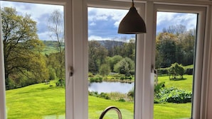 A kitchen with a sink and a view of a lake through a set of windows. - Spectacular setting in unspoilt East Devon, 15 minutes from Jurassic Coast. (Nr Honiton)