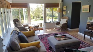 A spacious living room with a sofa, chairs, a coffee table, and a television. - Spectacular setting in unspoilt East Devon, 15 minutes from Jurassic Coast. (Nr Honiton)