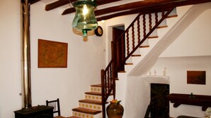 Eine Treppe mit Holzbalkonen, ein Holzstuhl, eine Vase mit Blumen und eine Karte an der Wand.