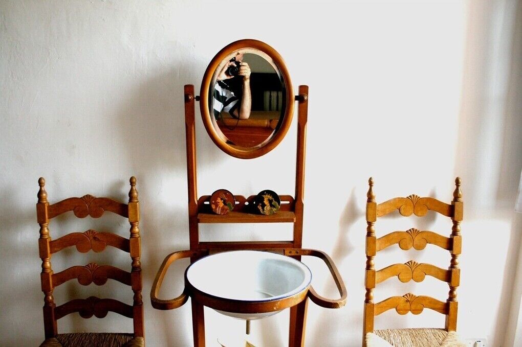 A wooden chair with a round mirror and a small table.