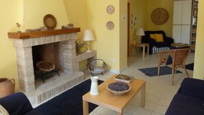 Un salon avec une cheminée, un canapé, une table agrémentée d’objets décoratifs et une bibliothèque.