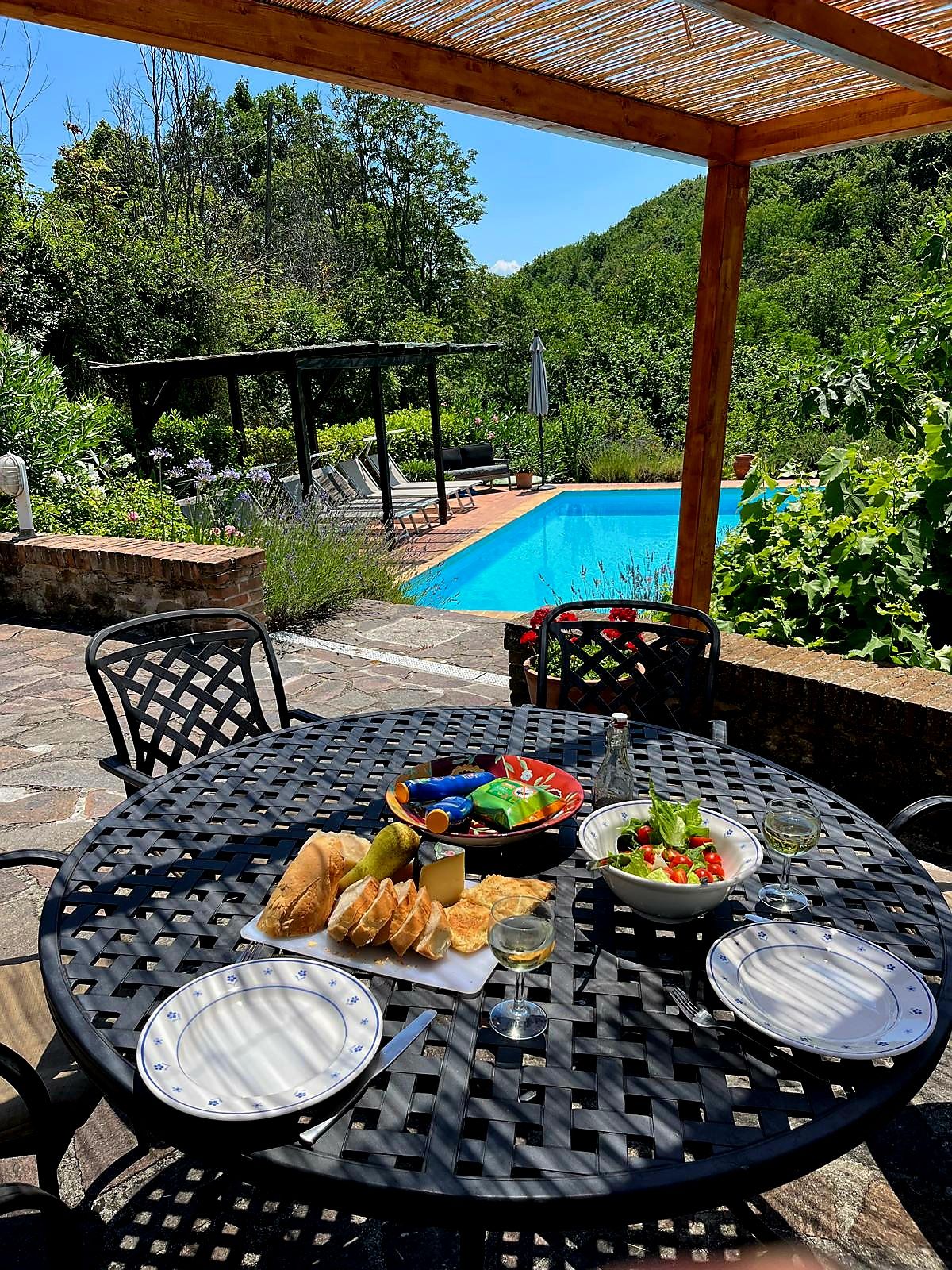 Un área de comedor al aire libre con una piscina de fondo.