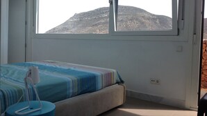 Un dormitorio con cama, una mesita de noche y una ventana con vistas a la montaña.