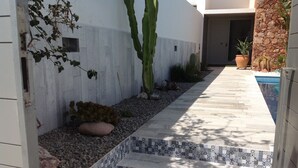Un camino que lleva a un área de piscina con un borde de azulejos y escalones.