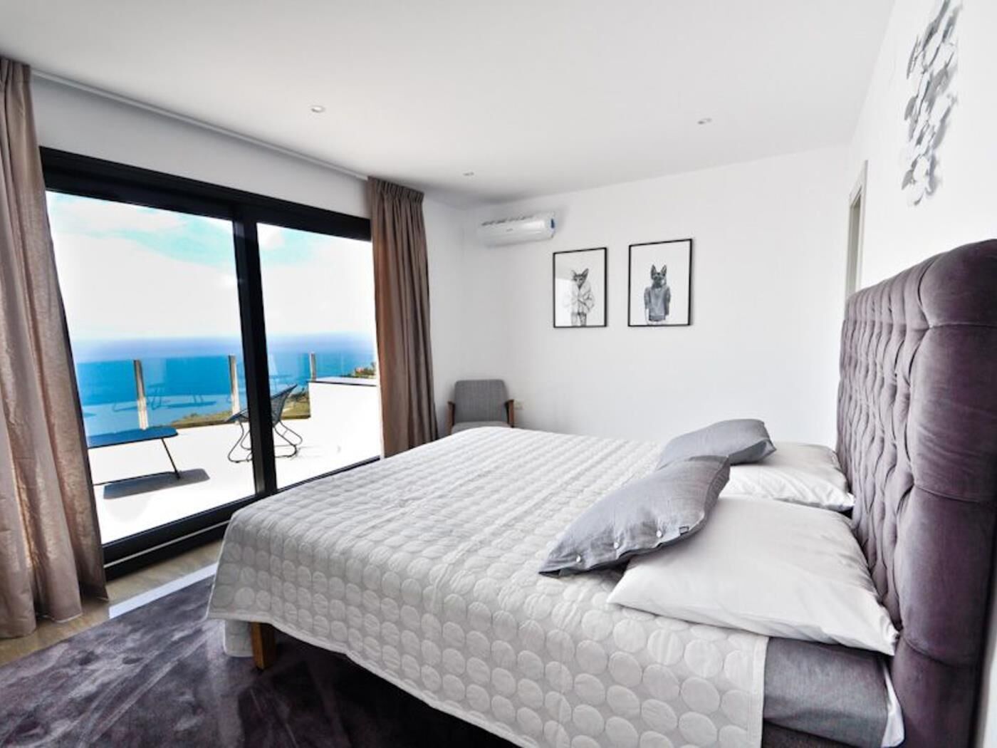 Un dormitorio con una cama grande, vista al mar y dos cuadros en la pared.