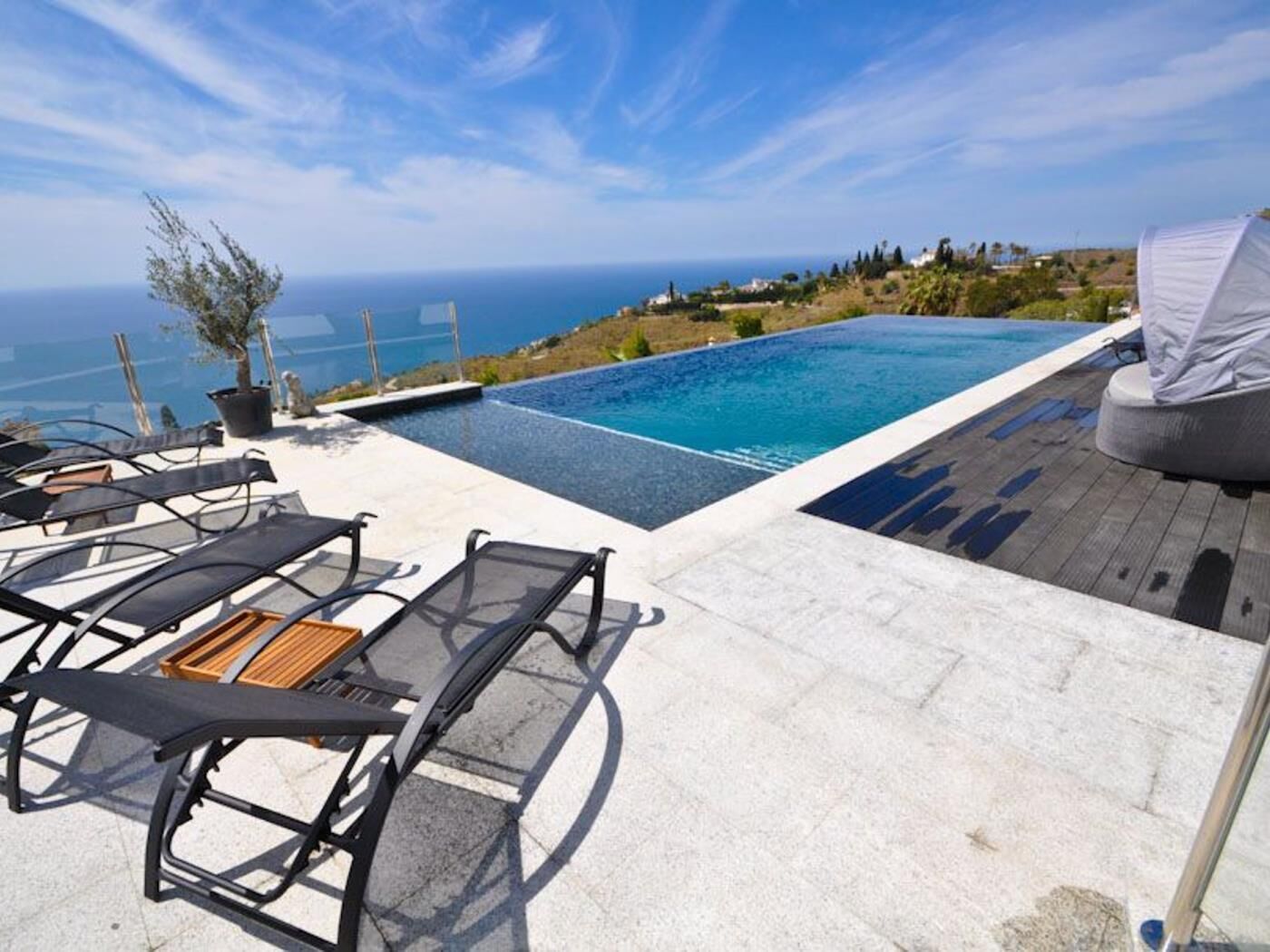 A rooftop infinity pool with lounge chairs and a view of the ocean.