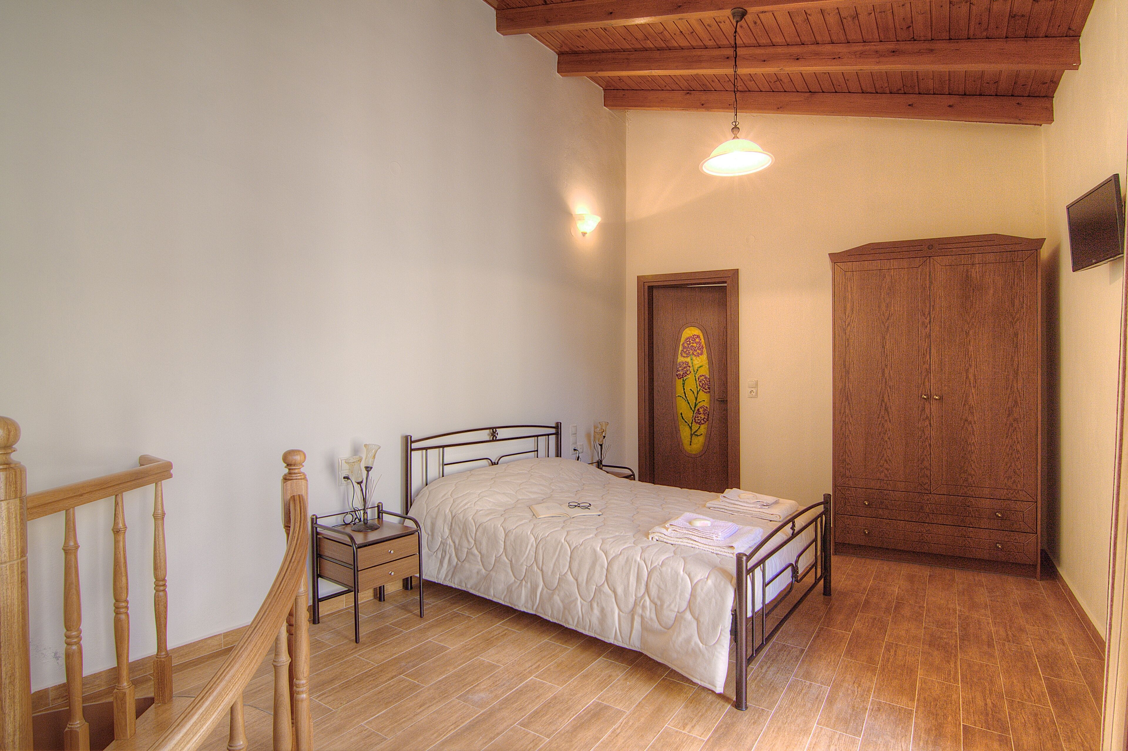 Una camera da letto con un letto di legno, un comodino, un armadio e una scala in legno.