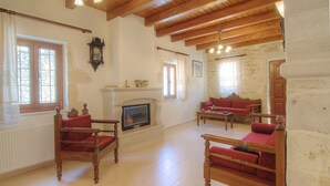 Un salón espacioso con chimenea, muebles de madera, paredes de piedra y ventanas amplias.