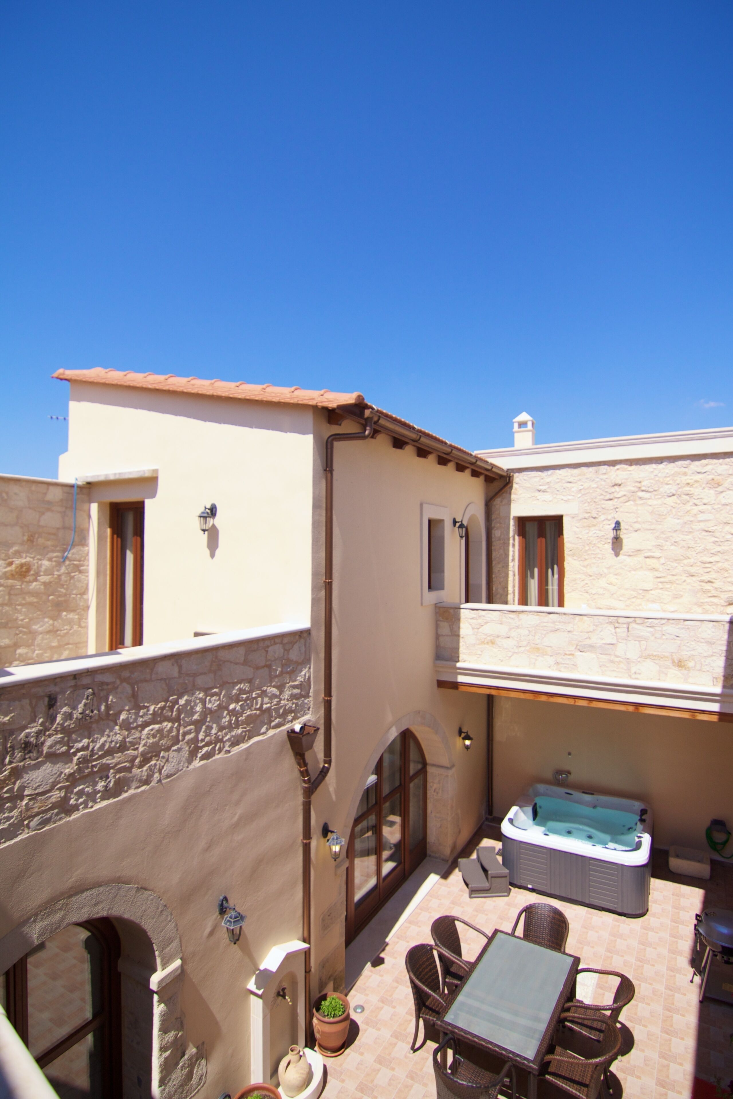 A courtyard with a stone wall, a hot tub, and outdoor furniture.