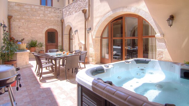 Un patio con jacuzzi, mobiliario exterior y un muro de piedra.