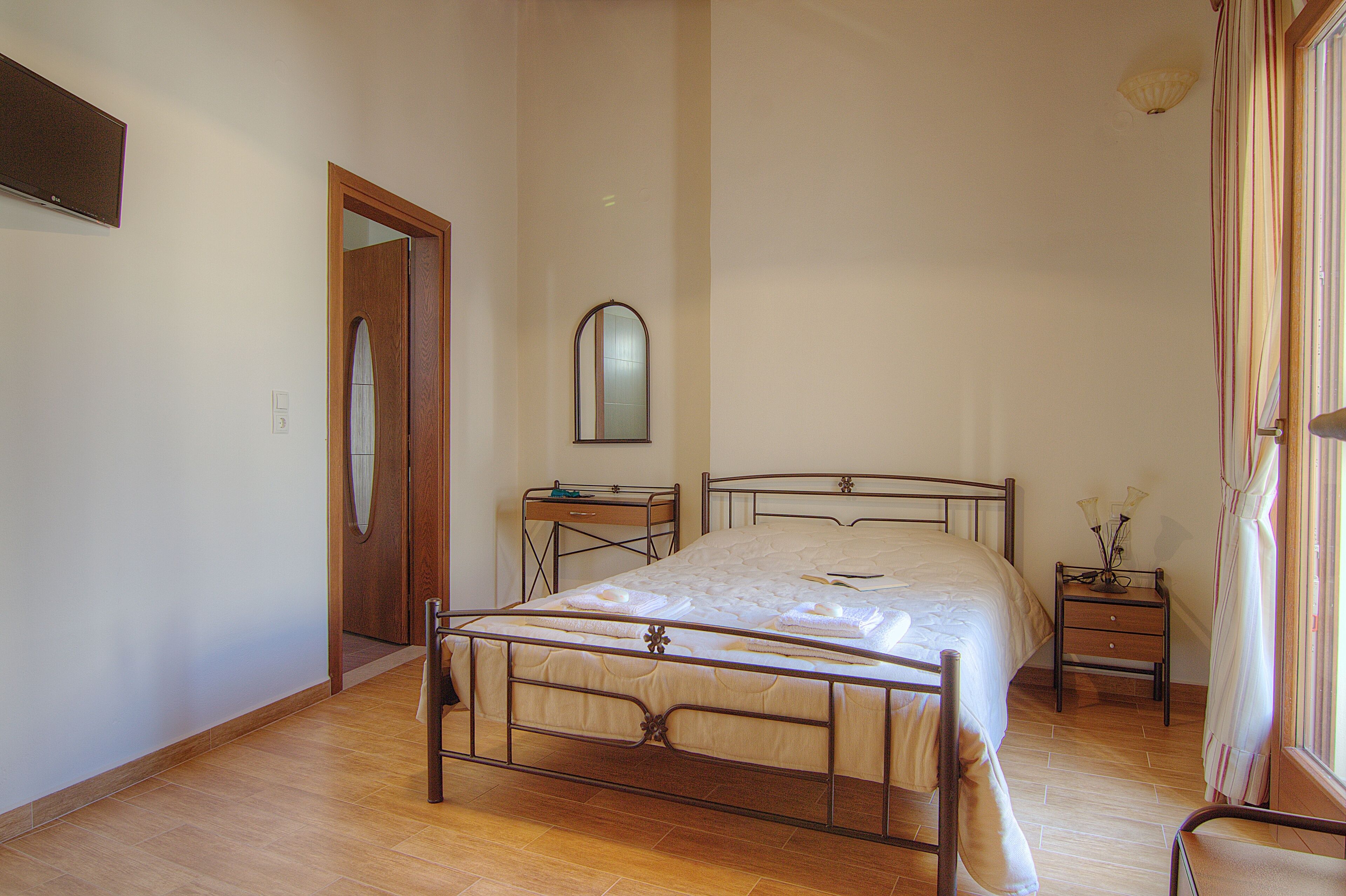 Ein Schlafzimmer mit Bett, Nachttisch, Spiegel und Tür.