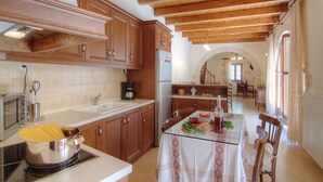 Una cocina con armarios de madera, una mesa de comedor con platos y una botella, y vistas al área de comedor.