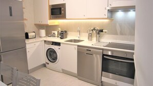 A compact kitchen with a washing machine, dishwasher, microwave, and oven. - EXCLUSIVE APARTMENT SEASIDE BEACH ZURRIOLA (Donostia)