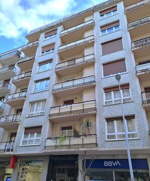 A multi-story building with balconies, a BBVA bank sign, and a visible storefront.