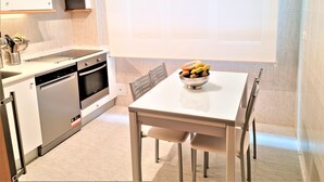 A modern kitchen with a dishwasher, oven, and a bowl of fruit on the table. - EXCLUSIVE APARTMENT SEASIDE BEACH ZURRIOLA (Donostia)