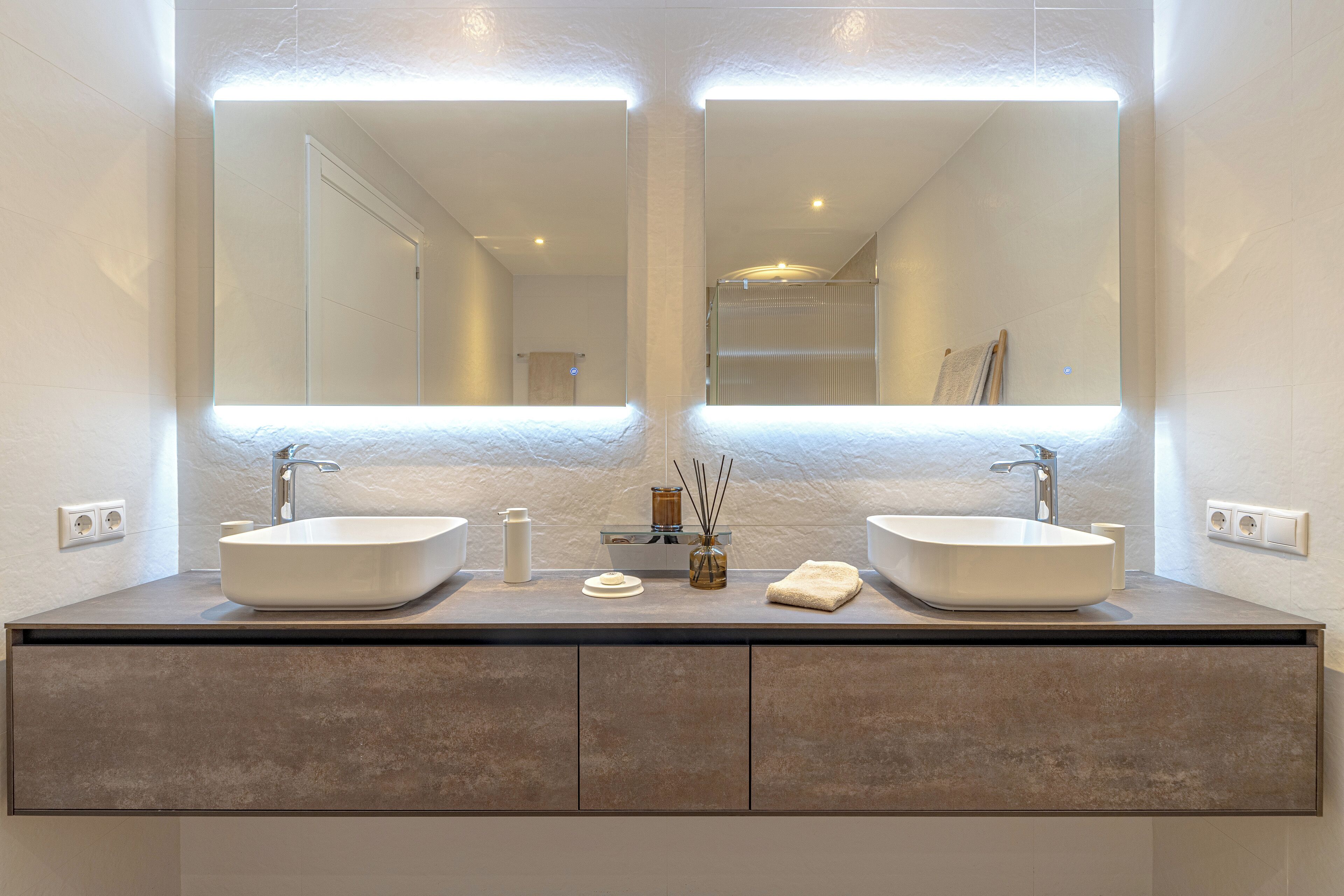 A modern bathroom with two large sinks, a mirror, and a cabinet below.