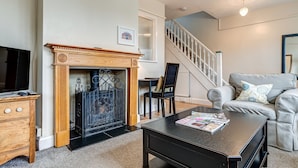 A living room with a fireplace, a staircase, a sofa, and a coffee table. - Lavender House | Oxford Holiday Let | 2 Bed & Sleeps 4 (Oxford)