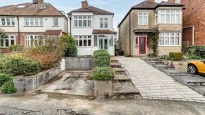 A row of terraced houses with a paved driveway and a yellow car parked on the right. - Lavender House | Oxford Holiday Let | 2 Bed & Sleeps 4 (Oxford)
