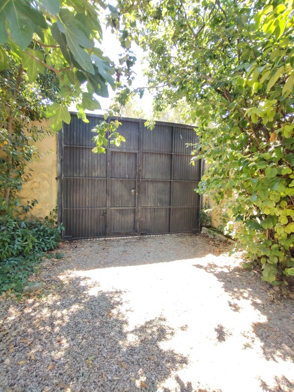 A gated area with a gravel path, surrounded by foliage and a wooden fence.