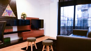 A modern living room with a sofa, two stools, a TV, and a bookshelf. - Fantastic Apartment in The City of Arts and Sciences (València)