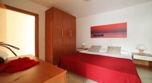 Una camera da letto con un letto, un armadio in legno, un comodino e un quadro appeso al muro.