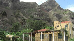 A yellow building with a red-tiled roof, surrounded by lush greenery and mountains in the background. - Chã de Arroz Country House (Ribeira Grande)