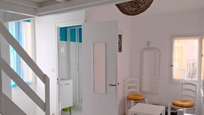 A spacious living area with a staircase, a dining table with chairs, and a view of the outside through a window. - House with character of  a fisherman (Collioure)