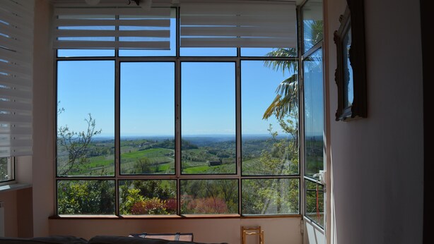A room with a large window offering a view of a green landscape.