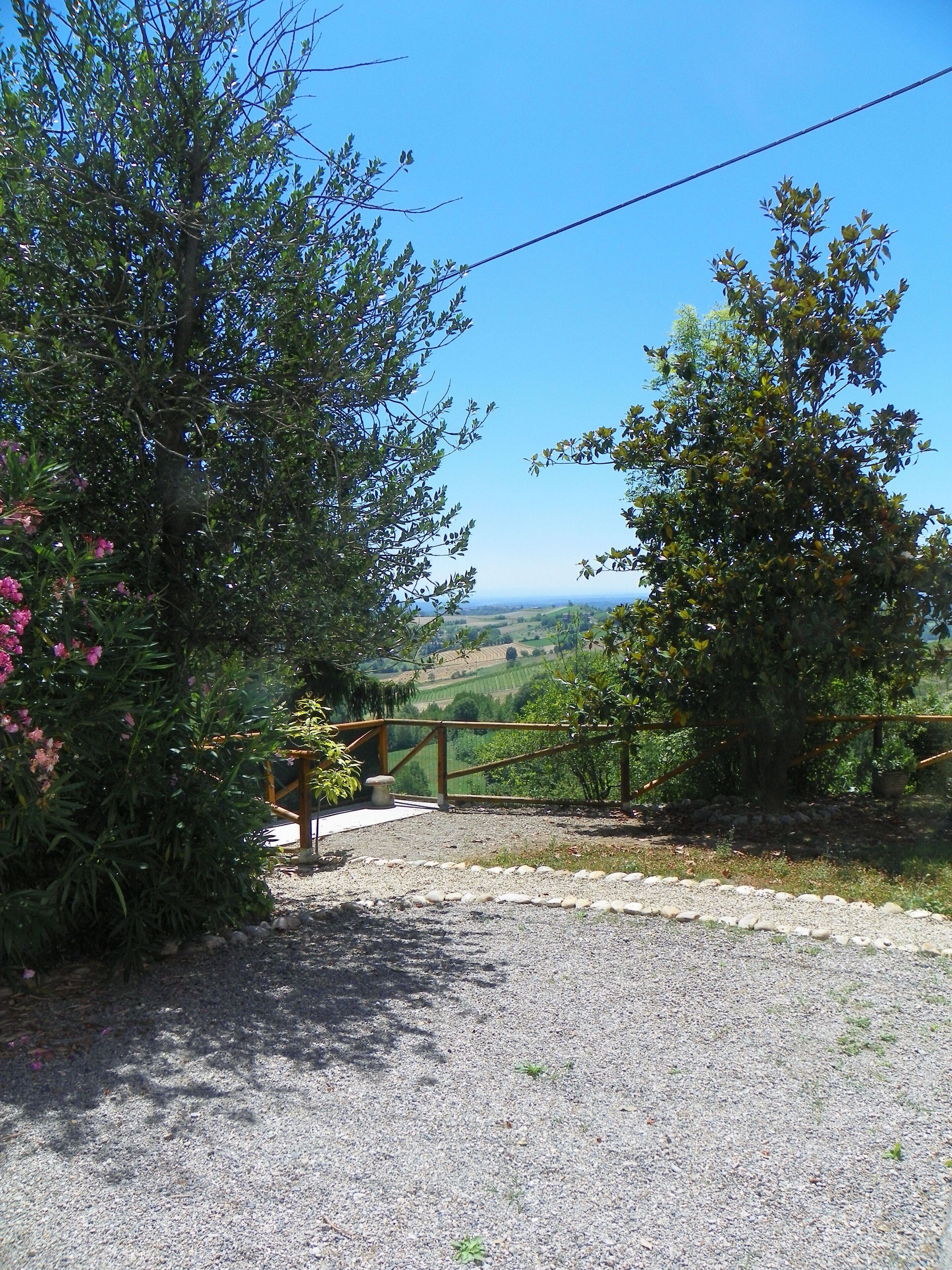 A gravel path leading to a wooden gate with a view of a hilly landscape.