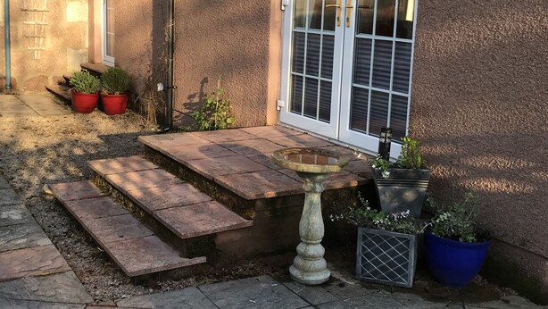 A house exterior with a stone staircase leading to a door, potted plants, and a birdbath. - The West Wing, your self contained luxurious rural haven. (Cammachmore)