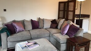 A living room with a sectional sofa, a small wooden table, and a magazine on the ottoman. - The West Wing, your self contained luxurious rural haven. (Cammachmore)