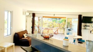 Una sala de estar moderna con un ventanal grande, un sofá, una mesa de centro y un televisor montado en la pared.
