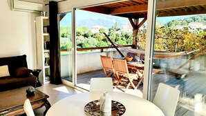 Una sala de estar moderna con un sofá blanco, una mesa de centro y un comedor con sillas de madera y una mesa de vidrio.
