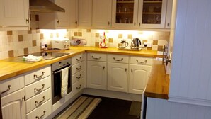 Una cocina con armarios blancos, encimera de madera, estufa y lavaplatos.
