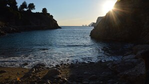A coastal scene with a rocky shoreline, calm sea, and a clear sky.