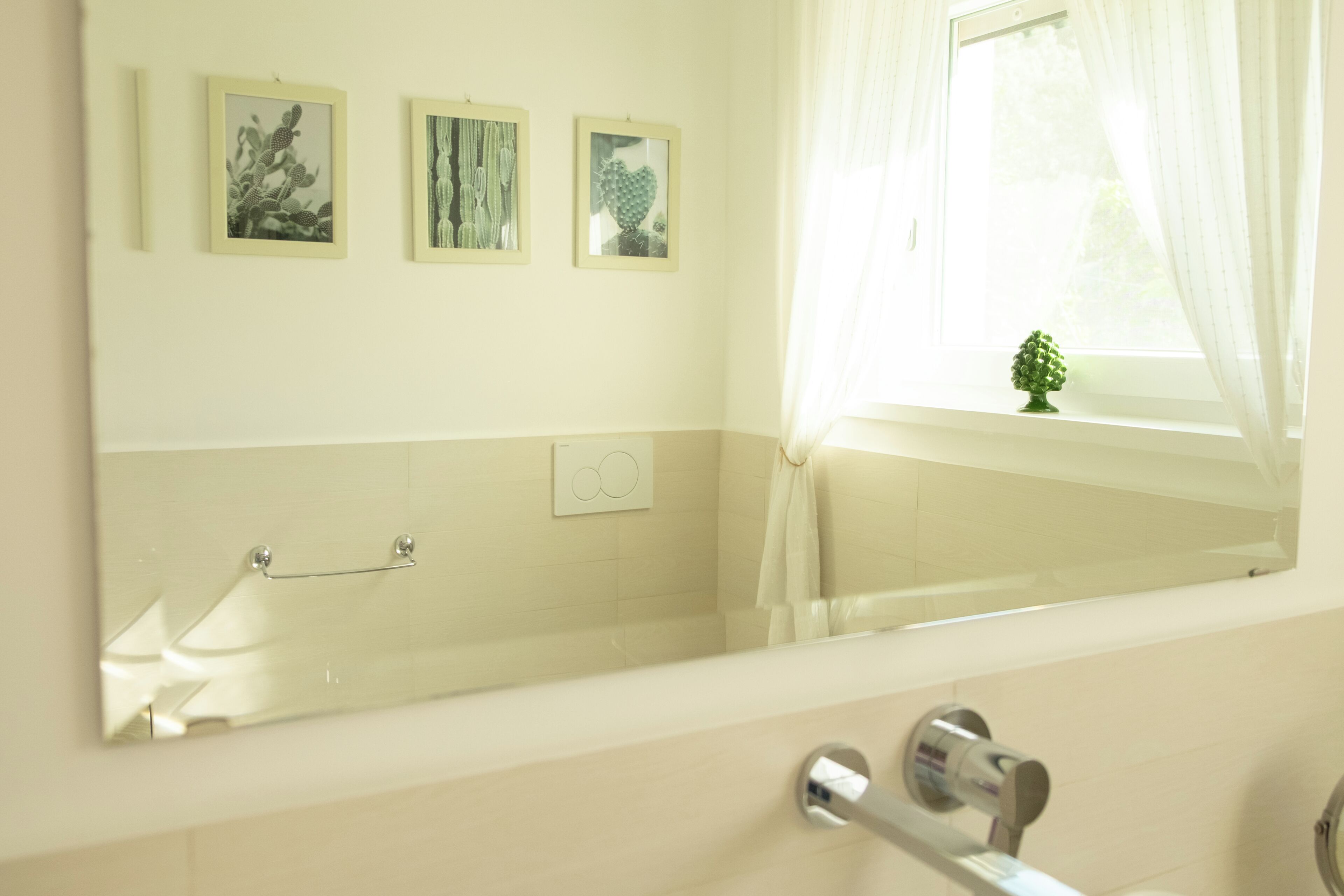 A bathroom with a bathtub, a towel rack, and three framed pictures on the wall.