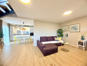 Una sala de estar moderna con un sofá, un comedor con sillas y una cocina al fondo.