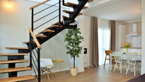 A modern living room with a wooden staircase, a dining area with white chairs, and a potted plant. - Villa Vedran - A Peaceful Retreat with Stunning Sea Views in Podgora (Podgora)