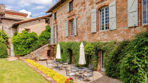 A courtyard with outdoor seating, a brick building, and a staircase leading to a balcony. - Maison Augustine – In the heart of Lisle-sur-Tarn (Lisle-Sur-Tarn)