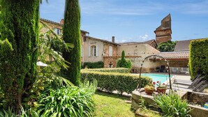 A courtyard with a swimming pool, surrounded by lush greenery and historic buildings. - Maison Augustine – In the heart of Lisle-sur-Tarn (Lisle-Sur-Tarn)
