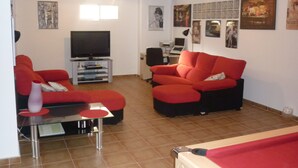 A living room with a red sofa, a TV, and a small table. - Villa with Private Pool and Large Underbuild (Gran Alacant)