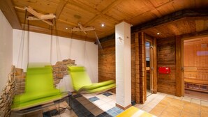 Un interior de madera con pared de piedra, una silla de masaje, una mesa de masaje y una puerta de madera.