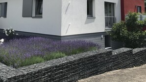 Une maison moderne à deux étages, dotée d’un toit en pente, de murs extérieurs blancs et d’un petit balcon.
